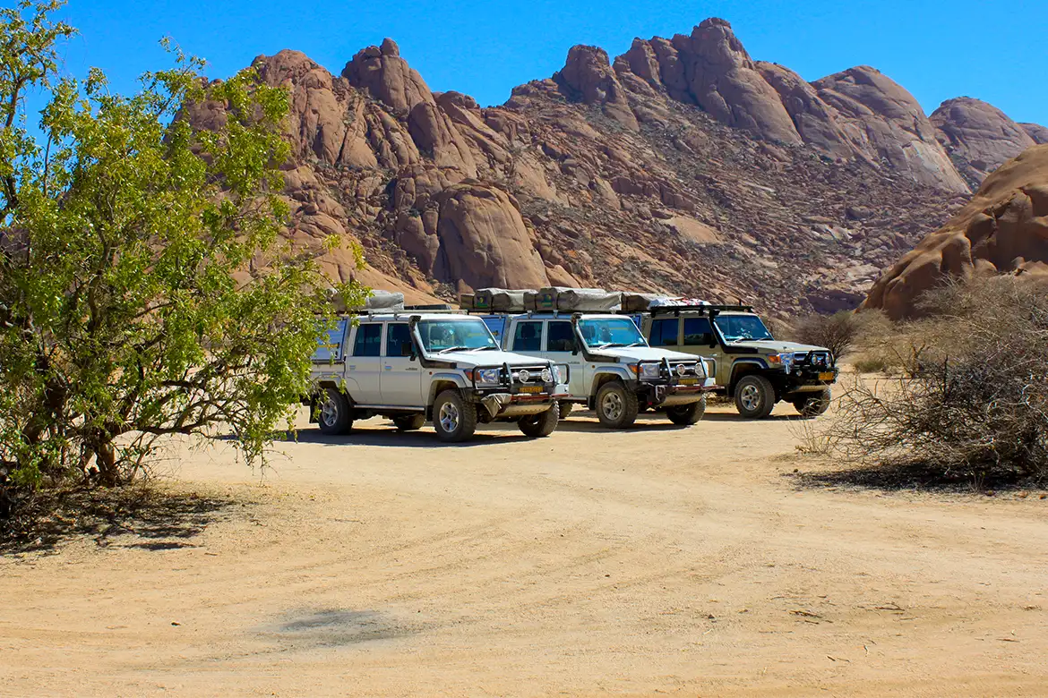 Drei geparkte, geführte 4×4-Safari-Fahrzeuge, Namibia Drei geparkte, geführte 4x4-Safari-Fahrzeuge, Namibia